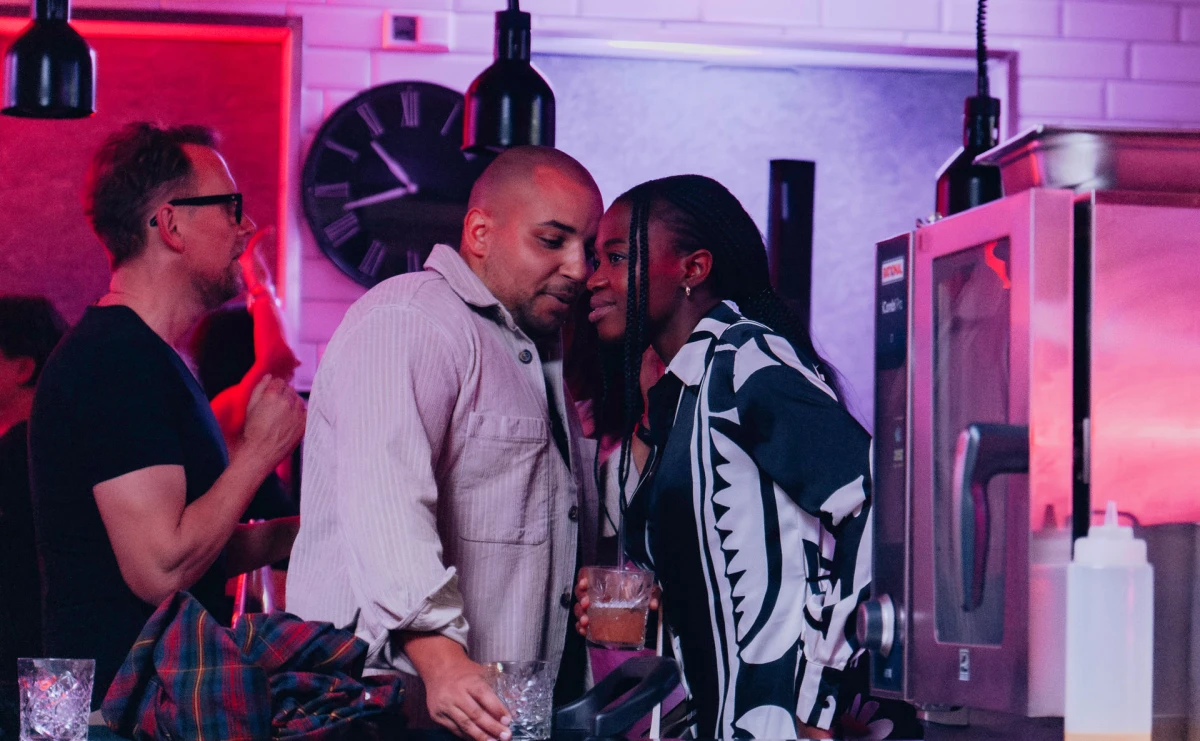 Junge Paare genie&szlig;en Cocktails in stilvollem Eventk&uuml;che-Ambiente.