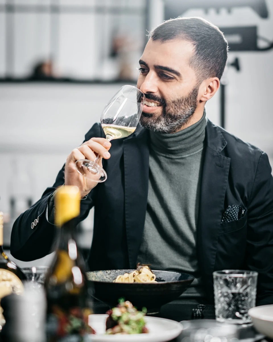 Mann genie&szlig;t Wein und Pasta in elegantem Restaurantambiente in Neuh&ouml;fer Stube.