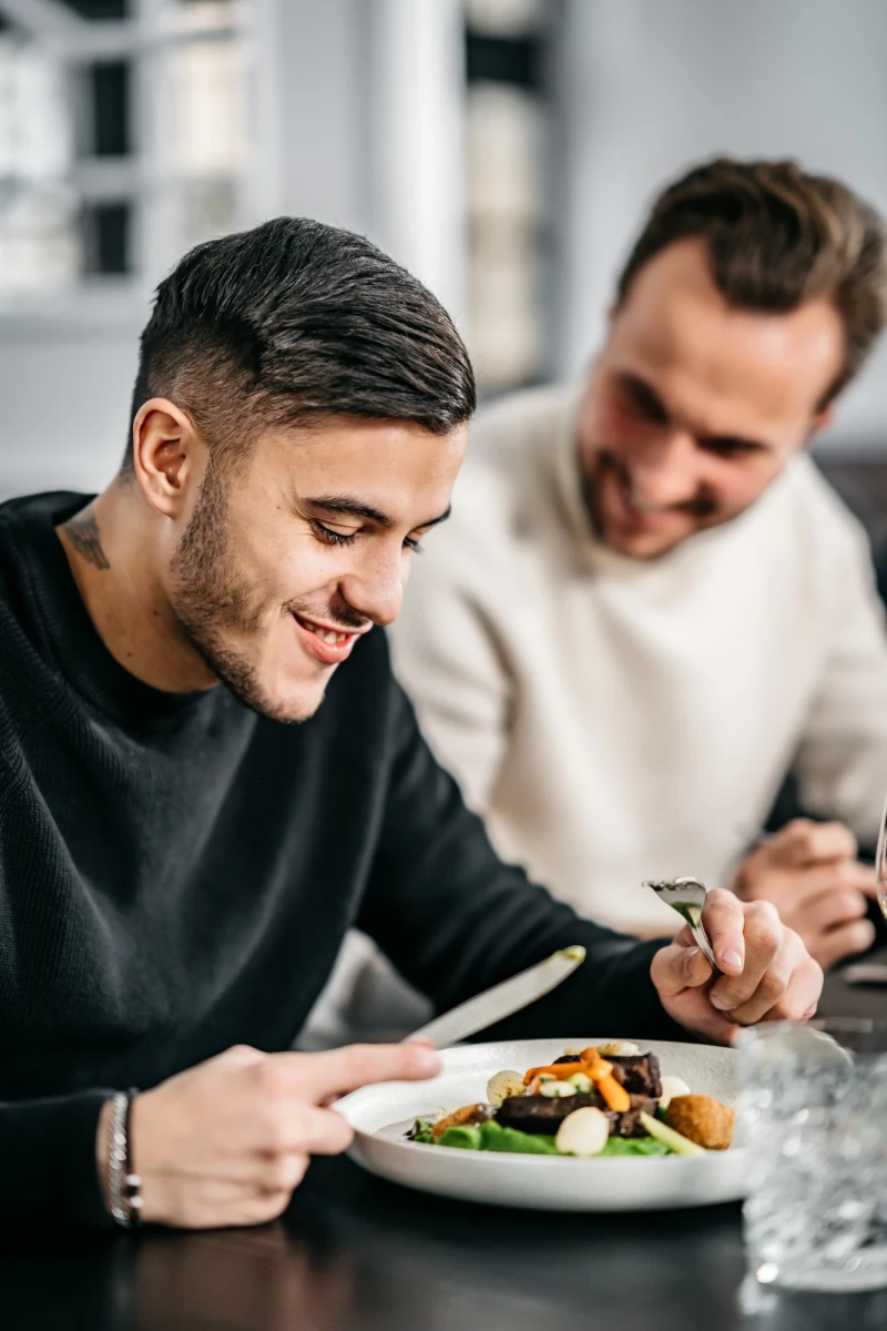 Zwei M&auml;nner genie&szlig;en k&ouml;stliches Essen im Hotel Riesengebirge.