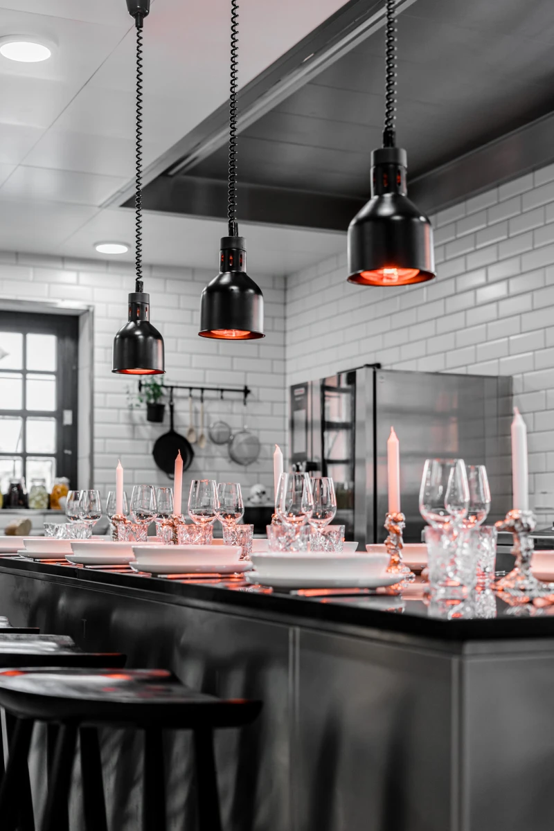 Moderne Eventküche mit stilvoll gedecktem Tisch und Beleuchtung.