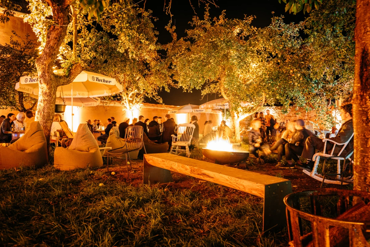 Gemütliche Abendstimmung auf der Obstwiese des Gutshof Neun mit Feuerstelle und beleuchteten Bäumen.