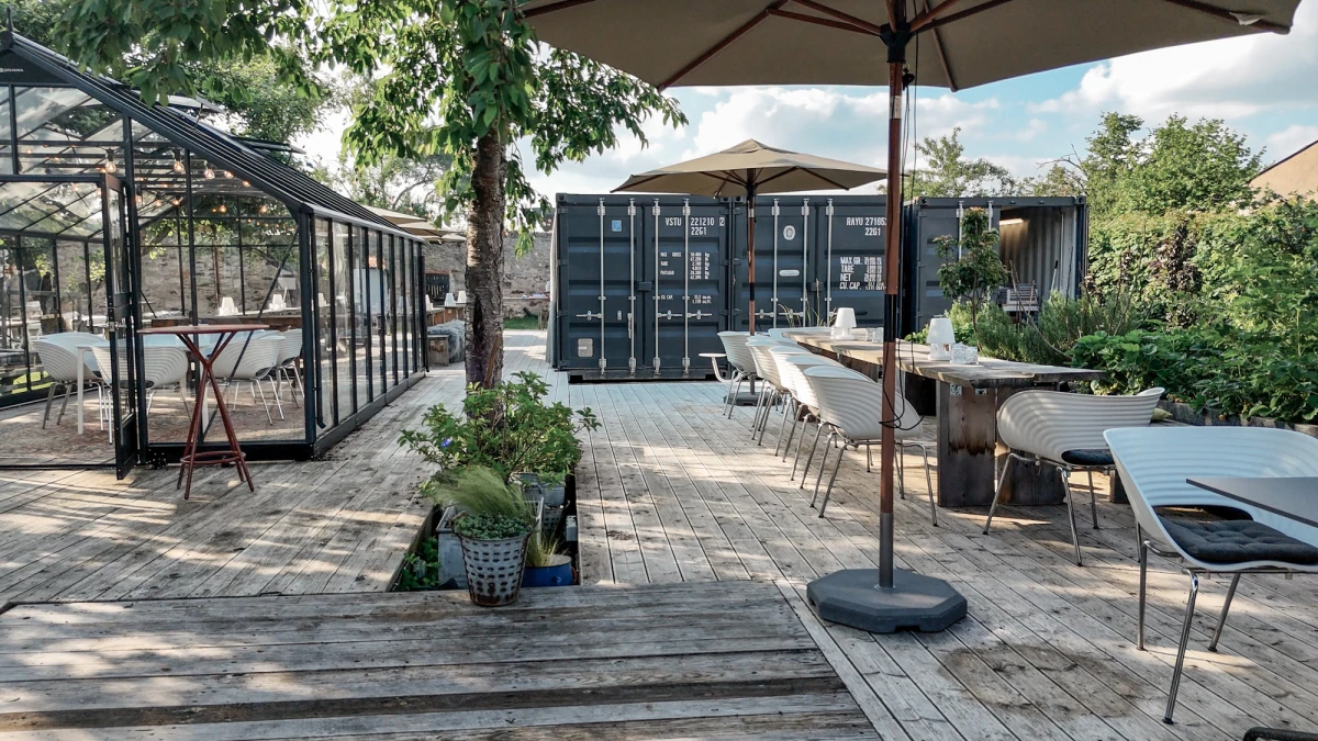 Stilvoller Au&szlig;enbereich mit Gartenm&ouml;beln und Glashaus auf der Obstwiese am Gutshof Neun.