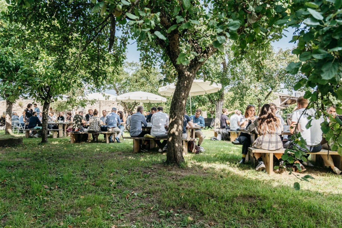 G&auml;ste genie&szlig;en Essen im Freien auf der Obstwiese am Gutshof Neun.