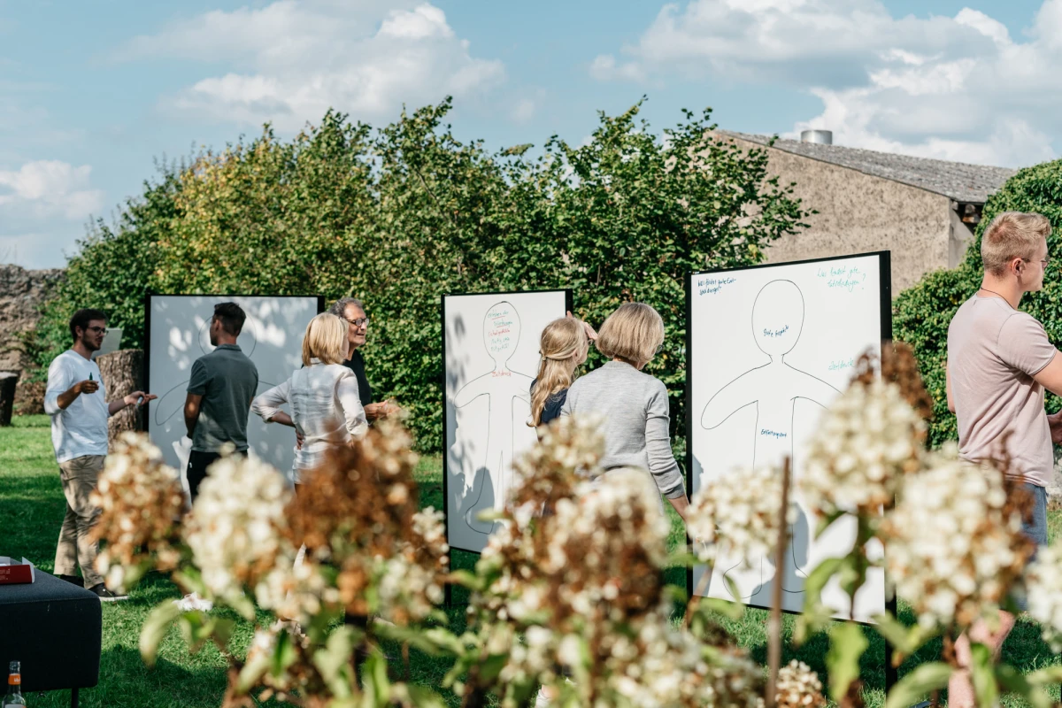Menschen auf der Obstwiese bei einer Outdoor-Tagung am Gutshof Neun.