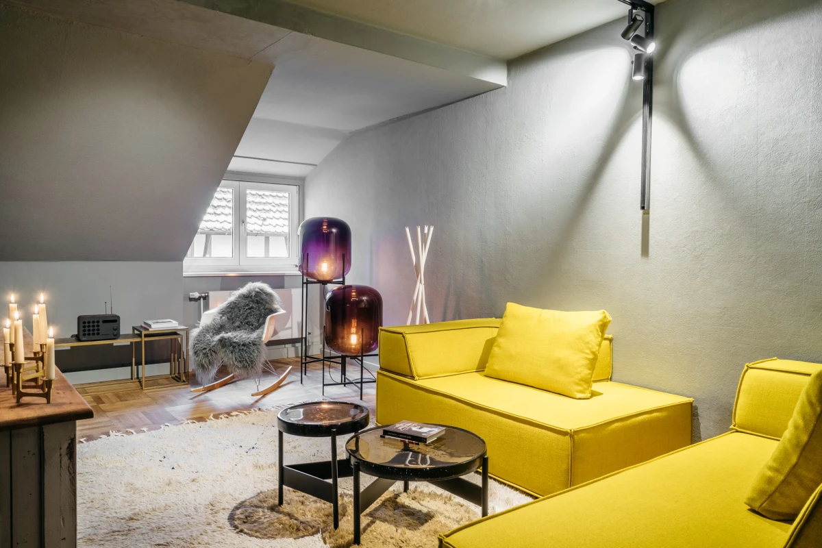 Stilvolles Wohnzimmer im Schwarzen Adler mit gelbem Sofa und Dekoration.